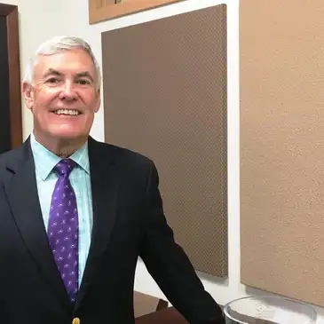 A man in suit and tie standing next to a wall.