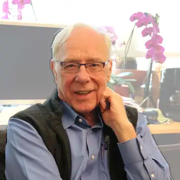 A man sitting in front of a window talking on the phone.