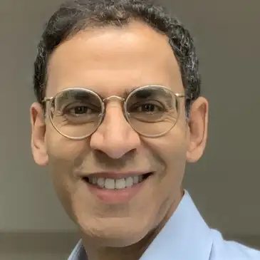 A man with glasses smiling for the camera.