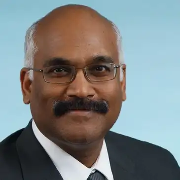 A man with a mustache and glasses wearing a suit.