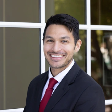 A man in suit and red tie standing outside.