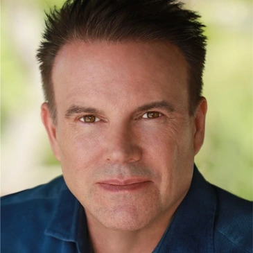 A man with spiky hair and wearing blue shirt.