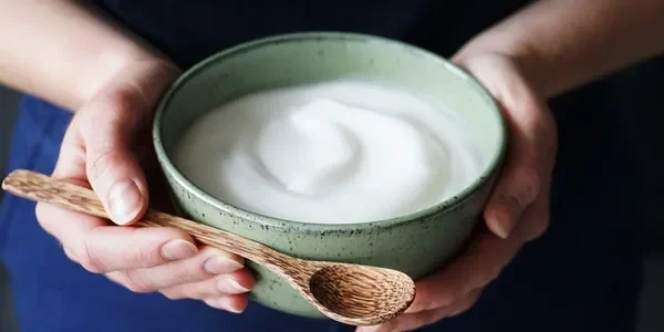 A person holding a bowl of milk with a wooden spoon.