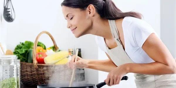 A woman cooking food in an oven with a basket of fruit.